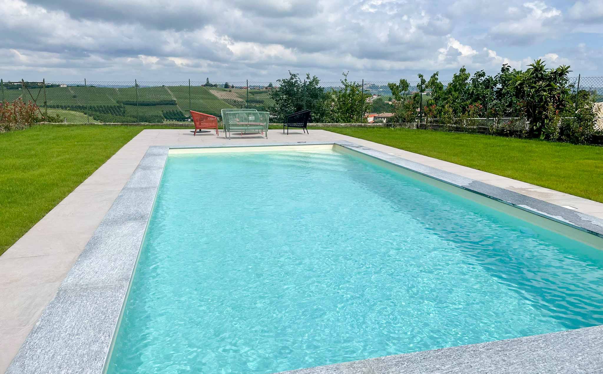 Zwembad omgeven door gras, tuinmeubelen en mooi uitzicht